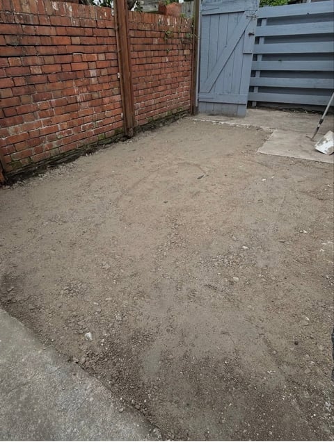 Concrete driveway alongside red brick wall and blue metal gate in residential area