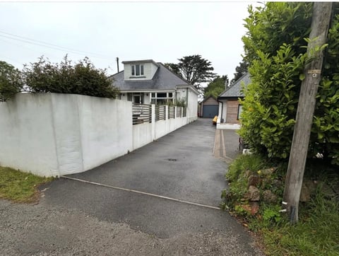 Residential driveway with white fence leading to a house with garage and landscaped grounds