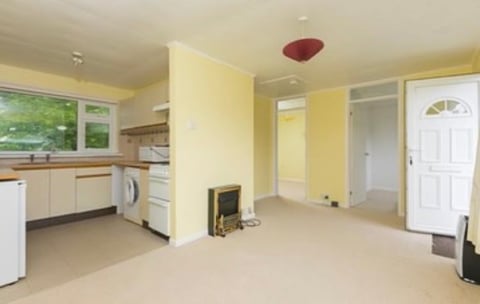 Spacious open-plan kitchen and living area with yellow walls, cream flooring, white appliances, and multiple doorways
